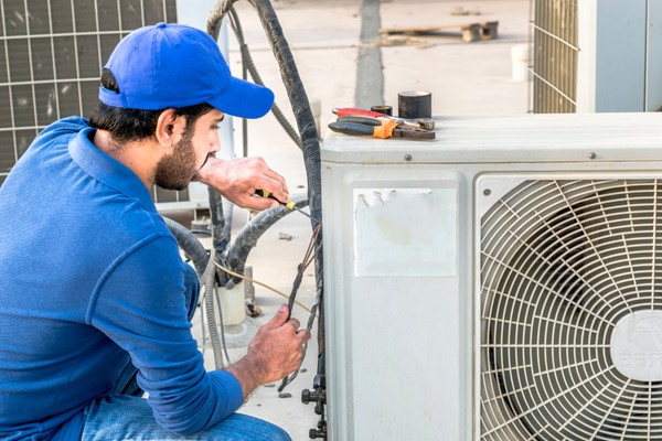 worker repairing air conditioner unit